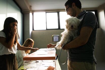 Un ciudadano vota junto a su mascota en un colegio electoral de Madrid. Los primeros sondeos de la 20.00 dan como ganador de las elecciones al PP, como después ha confirmado el escrutinio.