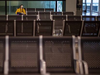 Un pasajero con mascarilla espera su vuelo en el aeropuerto de Barcelona.