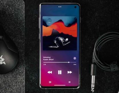 Aplicación de Spotify en uso y en la pantalla de un móvil