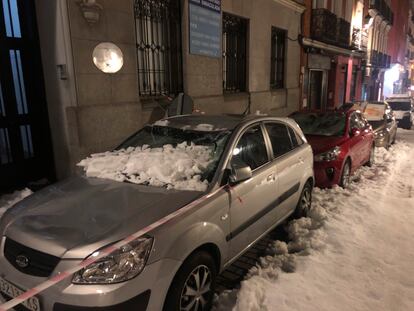 Varios coches con las lunas rotas por la nieve de los tejados tras el paso de 'Filomena' en la calle San Andrés del barrio de Malasaña.