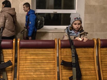 Una niña, apoyada en una silla donde descansa el arma de un policía, esperaba el viernes un tren para salir de Jersón hacia Kiev.