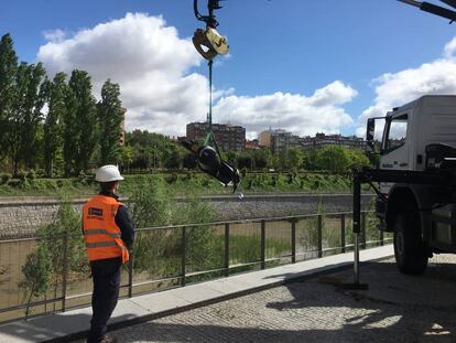 Los operarios recogen una motocicleta del río Manzanares.