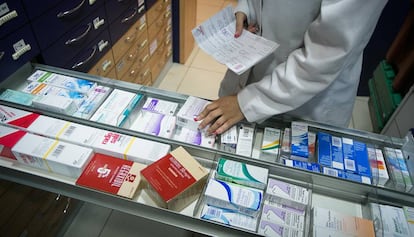 Una farmacèutica busca un medicament en una prestatgeria