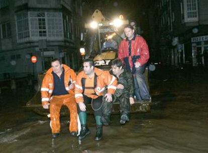 Fotografía del pasado 27 de noviembre de varios miembros de Protección Civil que cruzan, subidos en una excavadora, una calle de Vilagarcía de Arousa, anegada por las intensas lluvias.