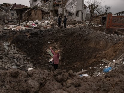 Una mujer en uno de los cráteres provocados por los misiles rusos en Hlevakha, a unos 30 kilómetros de Kiev, este jueves.