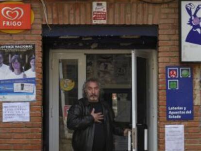 Un vecino sale de una tienda con una pancarta en defensa de las urgencias de Chiloeches.