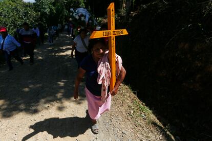 Una mujer lleva una cruz con el nombre de Eduar, de 24 años. "Solamente era un trabajador", explica su madre, Herminia, que insiste en que ninguno nunca "cargó un arma, solo el machete para trabajar".