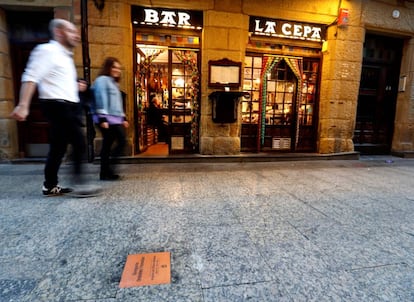 Dos personas caminan este domingo en San Sebastián junto a la placa de Gregorio Ordóñez, en la calle 31 de Agosto, después de que el Ayuntamiento la haya limpiado tras ser profanada de madrugada.