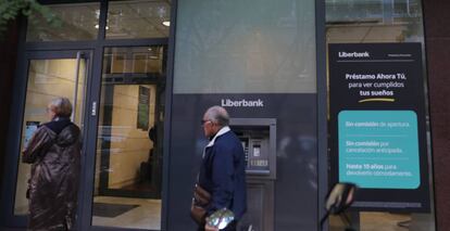 Dos personas pasan delante de una oficina de Liberbank.