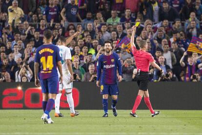 El árbitro muestra la amarilla a Messi durante el clásico. 