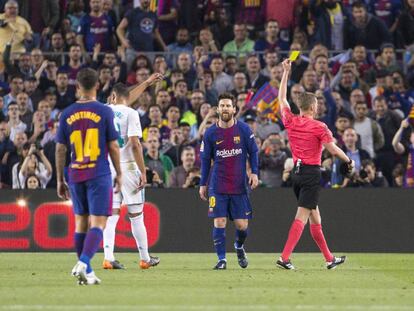 El árbitro muestra la amarilla a Messi durante el clásico. 