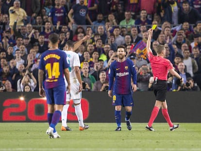 El árbitro muestra la amarilla a Messi durante el clásico. 