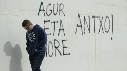 Un joven camina delante de una pintada en el País Vasco.