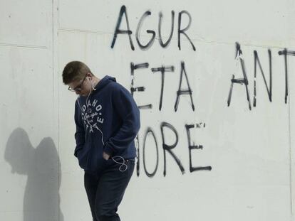 Un joven camina delante de una pintada en el País Vasco.