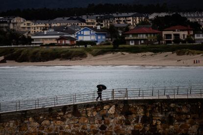 Una persona pasea por el puerto de Foz bajo la fina lluvia.
