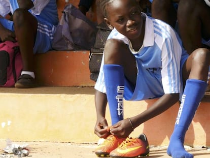 Una joven jugadora de fútbol gambiana se ata las botas.