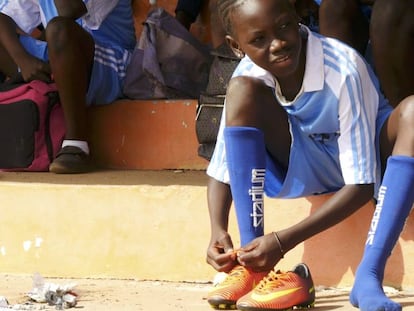 Una joven jugadora de fútbol gambiana se ata las botas.