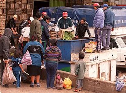 Hombres, mujeres y niños esperan para buscar alimentos entre los restos de un mercado en Buenos Aires.