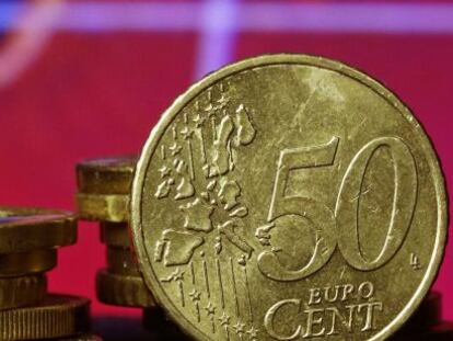 Monedas de medio euro frente a un chart de cotizaciones.