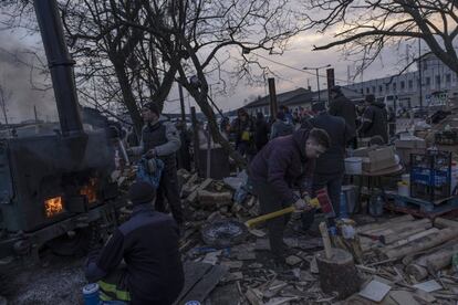 Un hombre corta leña mientras varios voluntarios ayudan a proporcionar agua caliente y comida en los alrededores de la estación de trenes en Lviv. El alto comisionado de las Naciones Unidas para los Refugiados, Filippo Grandi, ha confirmado en Bucarest que el número refugiados que han huido de Ucrania ha rebasado ya el millón de personas y las llegadas continuarán aumentando "si las acciones militares" no se detienen.