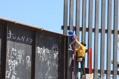 Una mujer ayuda a su hijo a trepar la valla fronteriza que divide a México y Estados Unidos en el tramo de Puente Negro, en Ciudad Juárez (México).