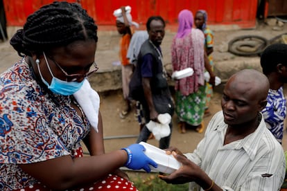 Una voluntaria distribuye comida a afectados por el confinamiento en Ghana.