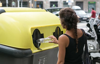 Una chica tira una botella en el contenedor amarillo en Barcelona, el 30 de julio de 2018.