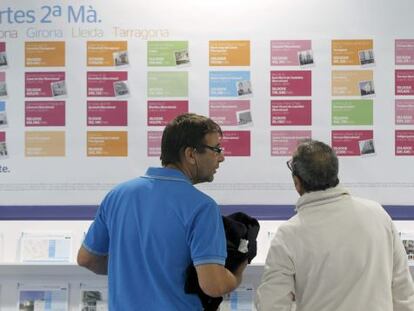 Unos visitantes del salón Barcelona Meeting Point observan un stand de una inmobiliarias.