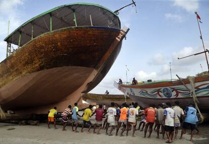 Una veintena de pescadores trasladan un bote a tierra, para salvaguardarlo de las lluvias monzónicas, en el distrito de Thane (India).