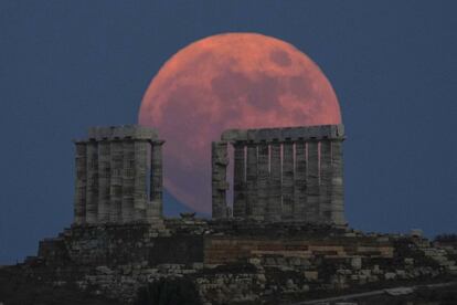 La Luna de fresa se eleva detrás del antiguo templo de Poseidón en Atenas (Grecia).