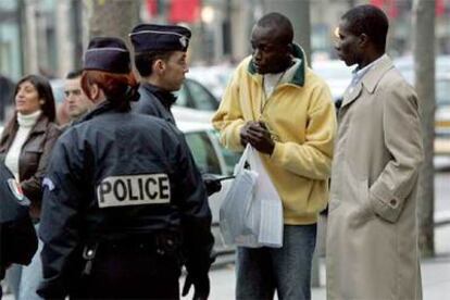 Un policía habla con dos viandantes en los Campos Elíseos de París ayer.