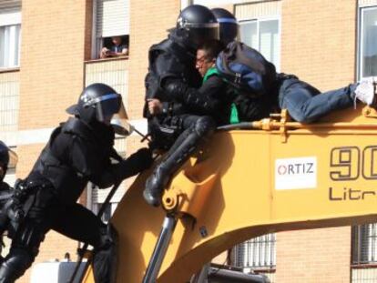 Police clash with residents who climbed on to the digger that demolished the building.