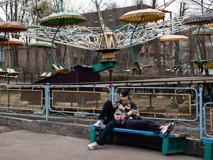 Una pareja mira sus teléfonos junto a una antigua atracción en el Parque de Cultura y Recreación Tarasa Shevchenka, en Berdichev, a finales de marzo.