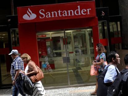 Gente caminando delante de una oficina de Banco Santander