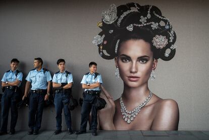 Agentes de la polica descansan ante una valla publicitaria cerca de la zona donde se concentran los manifestantes pro-democracia en Hong Kong.