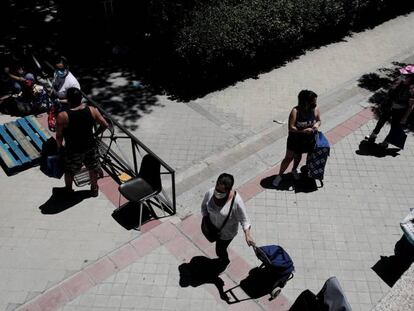 Colas de personas esperan a las puertas de la Parroquia Santa María Micaela para recibir ayuda alimentaria.