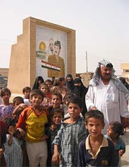 Un grupo de desplazados posa junto a un retrato de Sadam en Maqdadiya.