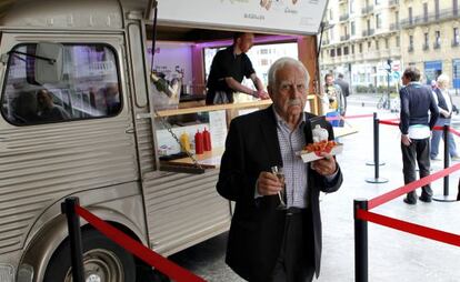 James Knappet ha convertido en plato de gourmet la comida rápida. Un visitante de la feria prueba uno de sus perritos calientes en San Sebastián