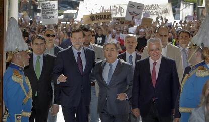 Juan Ignacio Zoido, que logró un histórico triunfo del PP en la ciudad de Sevilla, entra al Ayuntamiento acompañado por el presidente nacional del partido, Mariano Rajoy, y el autonómico, Javier Arenas. Al fondo, manifestantes del Movimiento 15-M agitan pancartas.