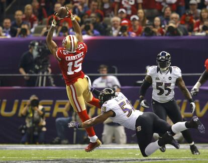 Michael Crabtree (15) de los San Francisco 49ers recibe un paso poco antes de ser derribado por Ray Lewis, estrella de los Ravens.