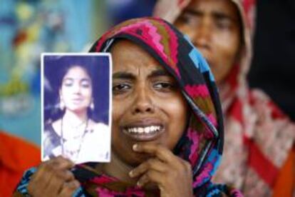 Una mujer muestra el retrato de una familiar víctima del derrumbe durante una oración especial por las víctimas del derrumbe del edificio Rana Plaza, cuando se cumple un año de la tragedia en Savar, Dacca (Bangladesh).