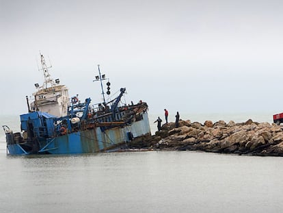 Varios técnicos observan ayer la draga encallada en la escollera del puerto de Cullera.