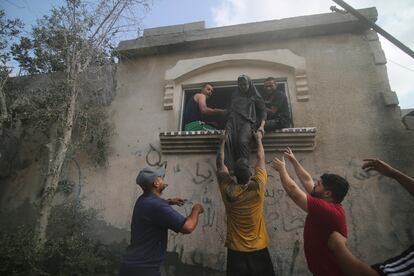 Un grupo de hombres ayuda a una mujer a salir de una vivienda dañada tras un ataque israelí en Rafah. 