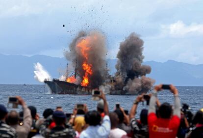 Una multitud toma fotografías de un barco en llamas en el pueblo de Morela, en la isla de Ambon, Indonesia.