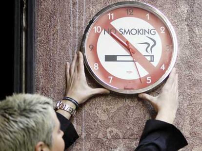 El tiempo corre para el tabaco en el trabajo. Una mujer coloca un reloj alusivo ayer en Bilbao.