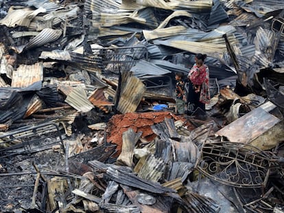 Una mujer con sus hijos regresan a sus refugios luego de que estos fueran devastados por un incendio en Daca (Bangladés), el 17 de agosto de 2019.