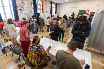 Ciudadanos franceses hacen cola mientras esperan para emitir su voto durante la segunda vuelta de las elecciones parlamentarias francesas en un colegio electoral en el distrito 18 de París.