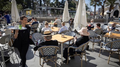 Una camarera atiende una terraza con turistas en Sevilla.