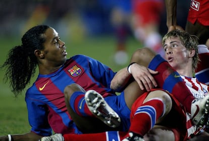 El jugador del Barcelona Ronaldinho y el delantero del Atlético Madrid Fernando Torres durante un encuentro de Liga de la temporada 2003 - 2004. El encuentro terminó 3 a 1 para los blaugranas. .