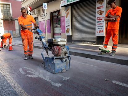 Un operario borra la señal del carril bici, en la avenida Juan Carlos I de Elche.